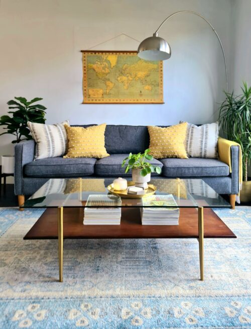 Mid-century style living room with coffee table, grey sofa, yellow cushions and arco lamp.